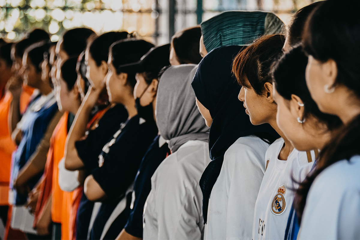 19 girls standing in a line looking away from the camera