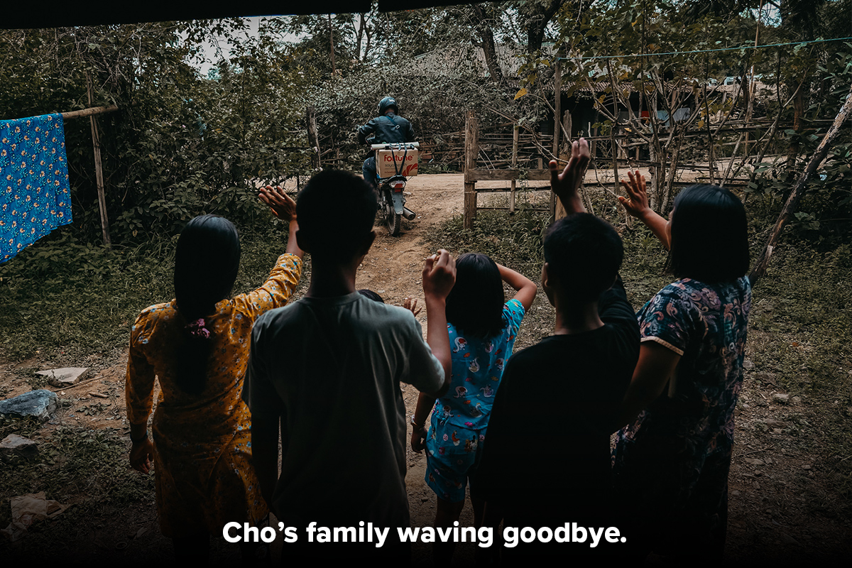 Family waving goodbye as man leaves on motorbike for training