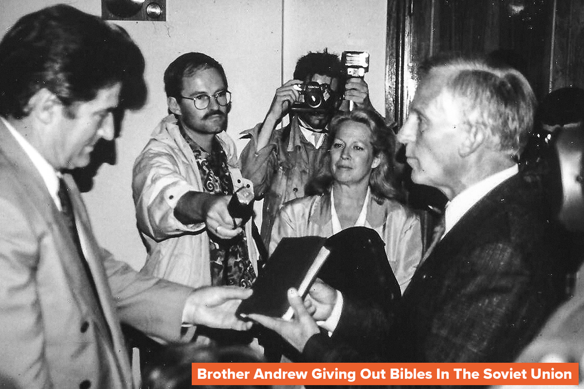 a black and white photo of Open Doors founder Brother Andrew passing a Bible to a Christian from the Soviet Union